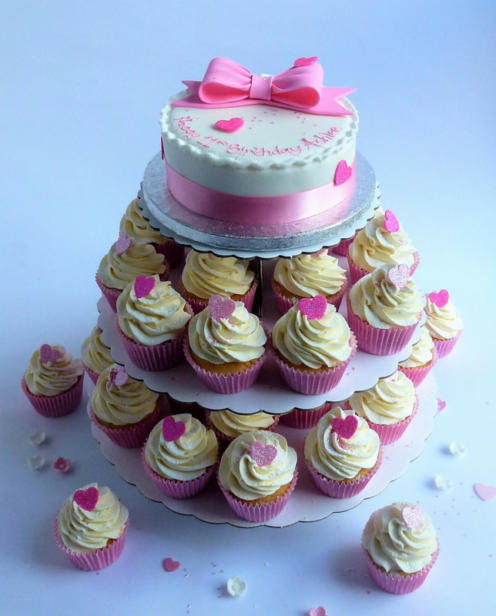 Round cake with cupcakes on stand with bow decoration